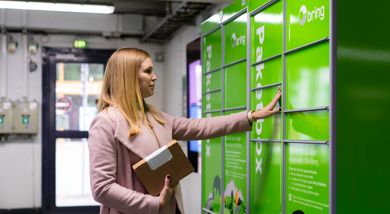 Kvinna hämtar paket från Bring-boxar