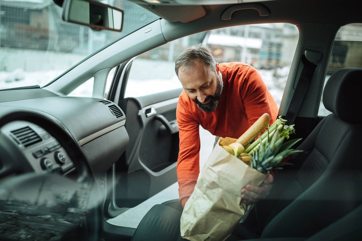 Bild av man som stoppar in en kasse med matvaror i bilen